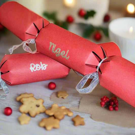Handmade Crackers, Two red handmade crackers on a Christmas Table.