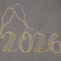 Detailed view of gold foiled “2026” with champagne glasses design on black cracker card.