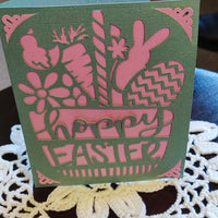 Easter greeting card featuring bunny and floral cut-outs in green and pink, with 'Happy Easter' text.