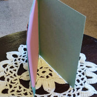 Inside view of Easter greeting card with green and pink cut-out design, displayed on a lace doily.