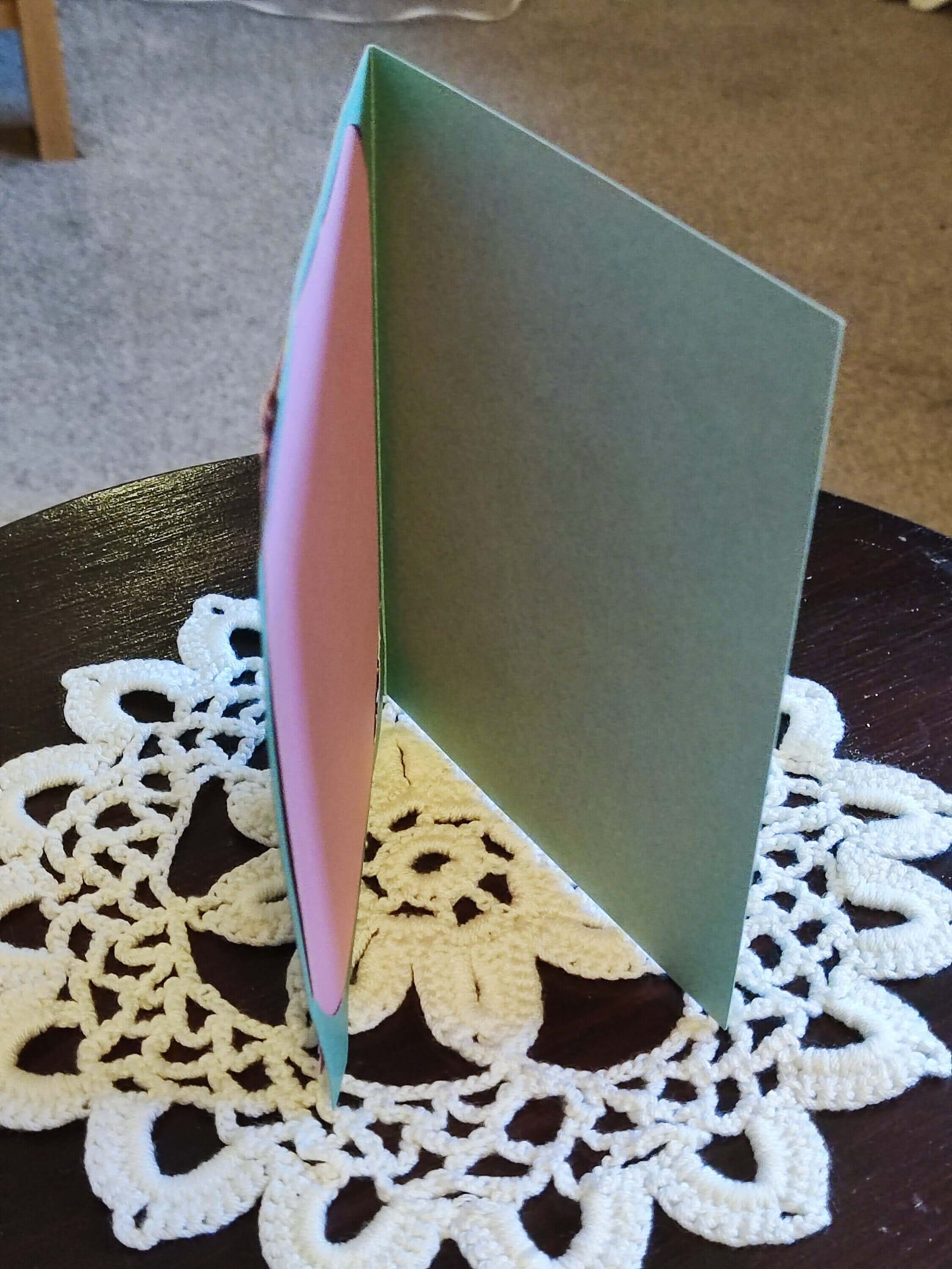 Inside view of Easter greeting card with green and pink cut-out design, displayed on a lace doily.