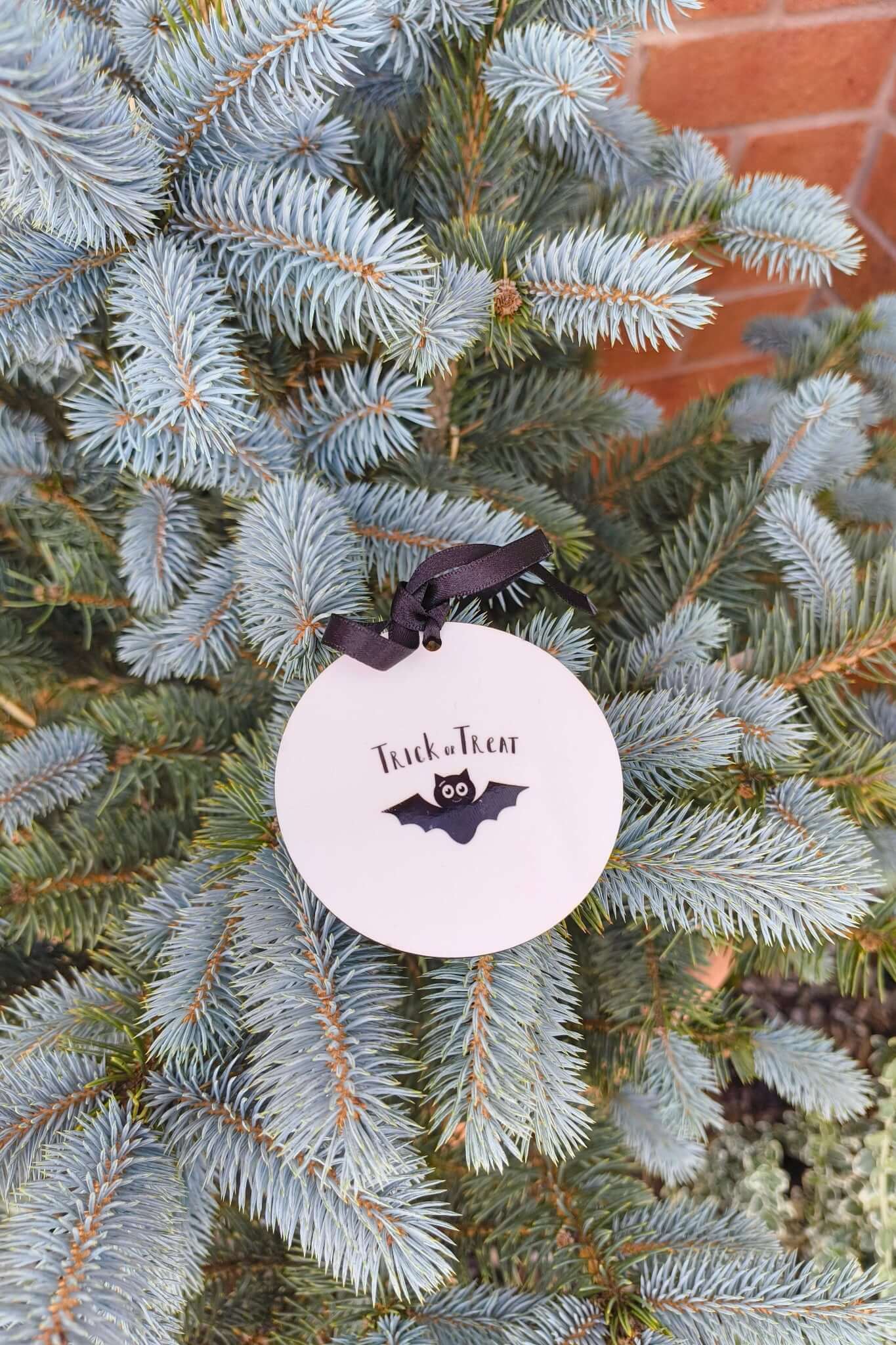 Close-up of Halloween bauble with bat and Trick or Treat design, tied with black ribbon.