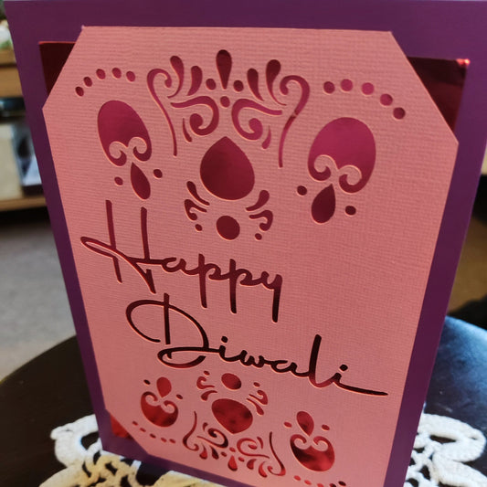 Handmade Diwali card with intricate cut-out design in pink and purple, featuring 'Happy Diwali' greeting.