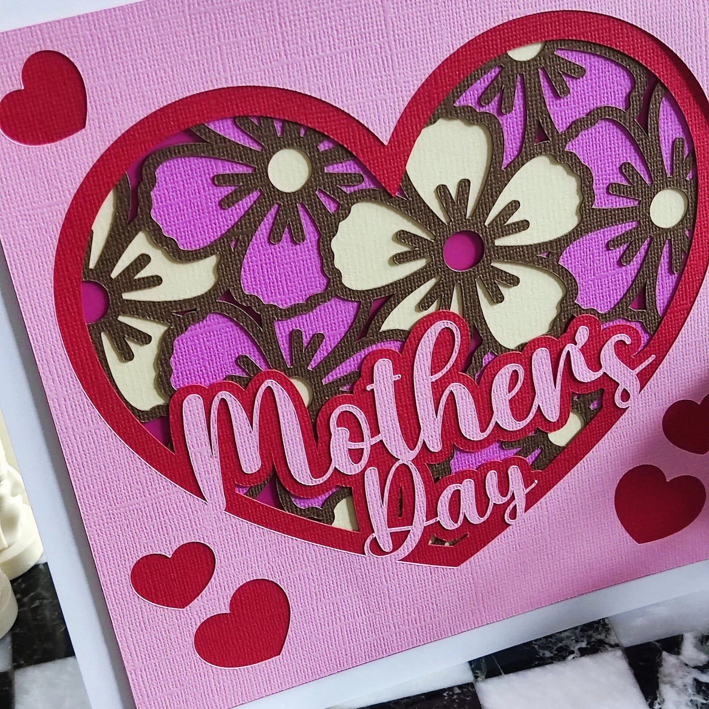 Handmade Mother's Day card with floral heart design in pink and purple, featuring layered cut-out flowers.