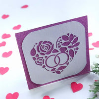 Handmade wedding or anniversary card with a sparkly purple background and a white die-cut floral heart design with wedding rings.
