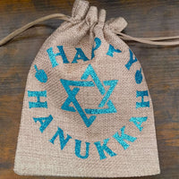 Drawstring Hanukkah hessian bag cinched at top with visible blue glitter Star of David and lettering