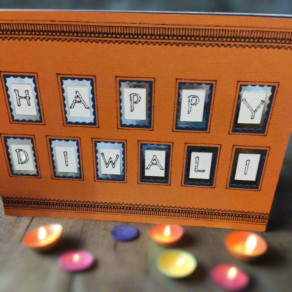 Handmade Happy Diwali card with festive orange design and decorative letters, surrounded by colorful diyas.