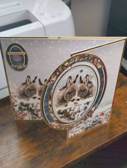 Handmade Christmas card featuring snowy scene with a donkey design and decorative elements.