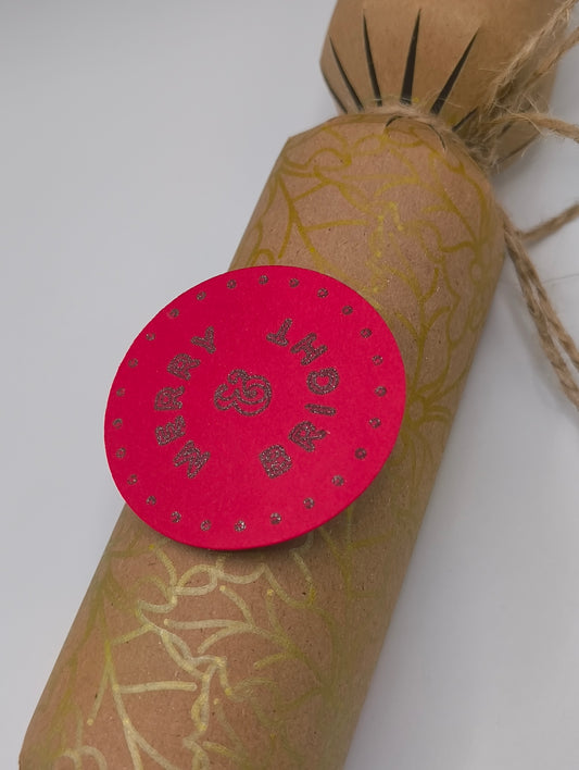 Eco-friendly Christmas crackers with gold holly design and festive pink tag, perfect for the holiday table.