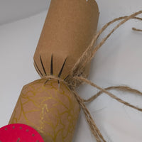 Eco-friendly Christmas crackers with gold holly design and jute twine, rustic festive style.