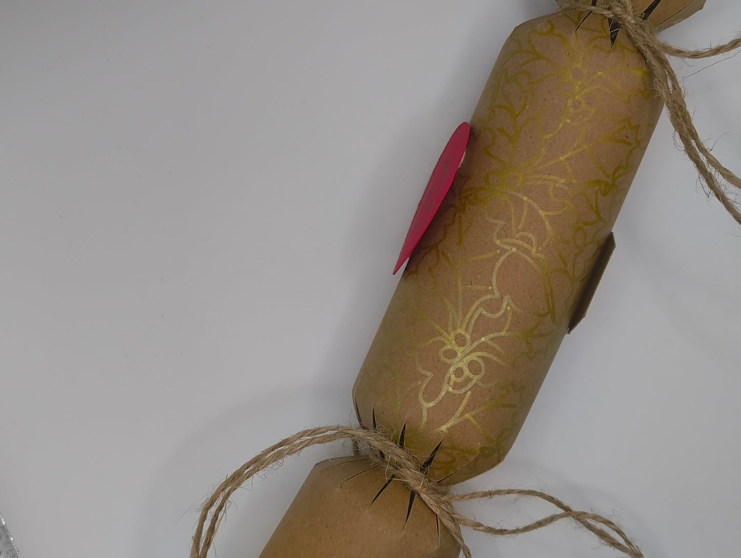 Eco-friendly Christmas crackers with gold holly design and natural jute twine for a rustic festive look.