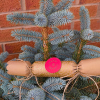 Eco-friendly Christmas crackers with gold holly design displayed on a Christmas tree.