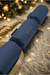 Navy blue personalised Christmas cracker with gold ribbon, displayed on a cosy fur rug with festive tree lights twinkling in the background.