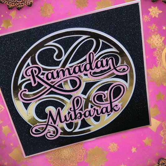 "Ramadan Mubarak" card with glittery black background and gold and pink lettering, on a festive pink and gold background.