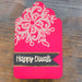 Angled side view of red Diwali tag with gold embossed floral design and black ribbon banner reading Happy Diwali