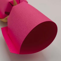 Close-up of a handmade personalised birthday cracker in vibrant pink, showcasing its unique design and texture.