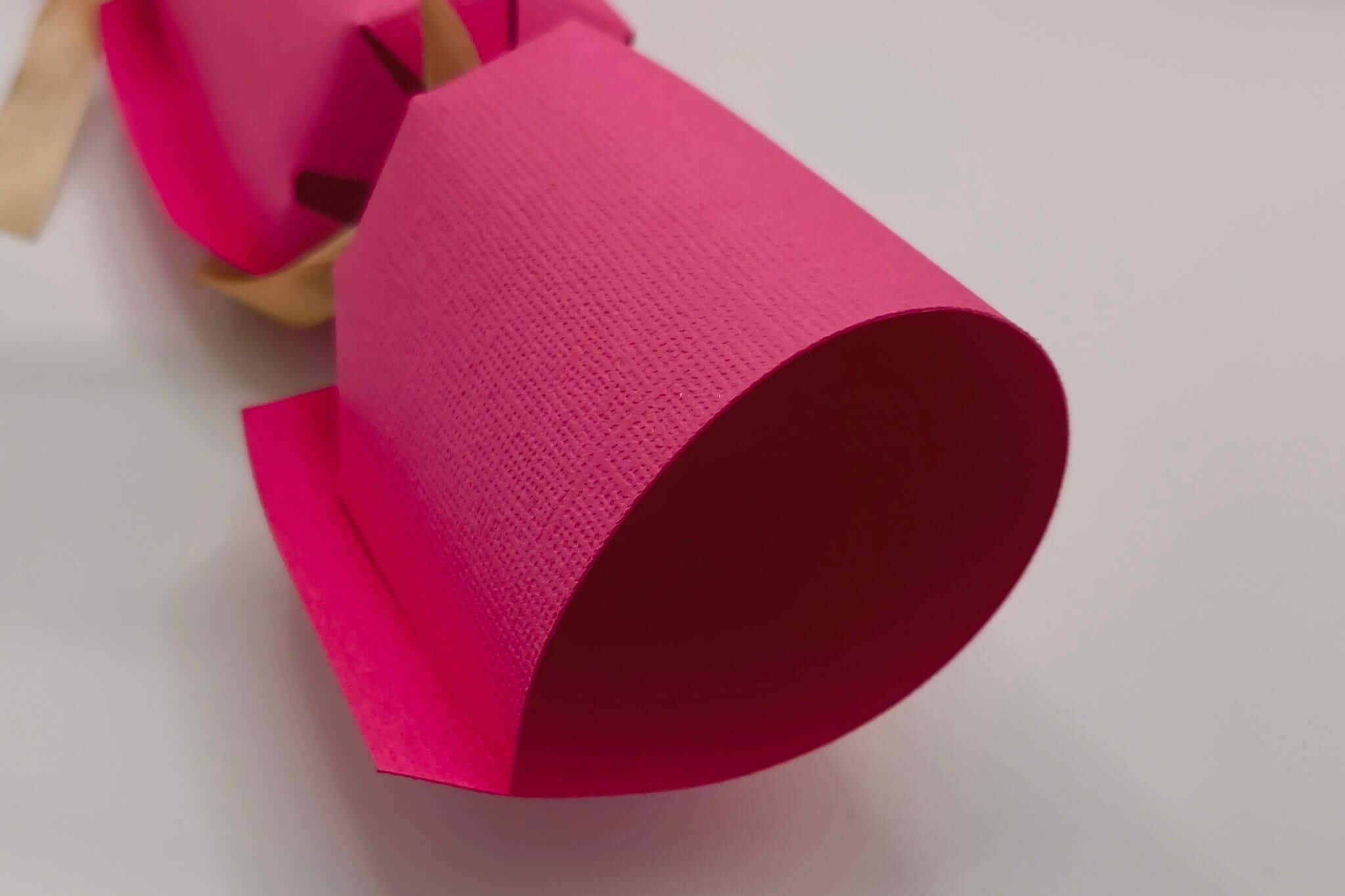 Close-up of a handmade personalised birthday cracker in vibrant pink, showcasing its unique design and texture.