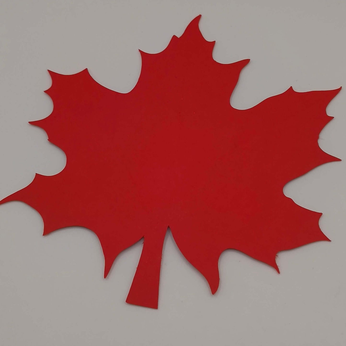 Blank red maple leaf cut from cardstock, ready to be personalised as a name place card or decoration for autumn, weddings, or Thanksgiving.