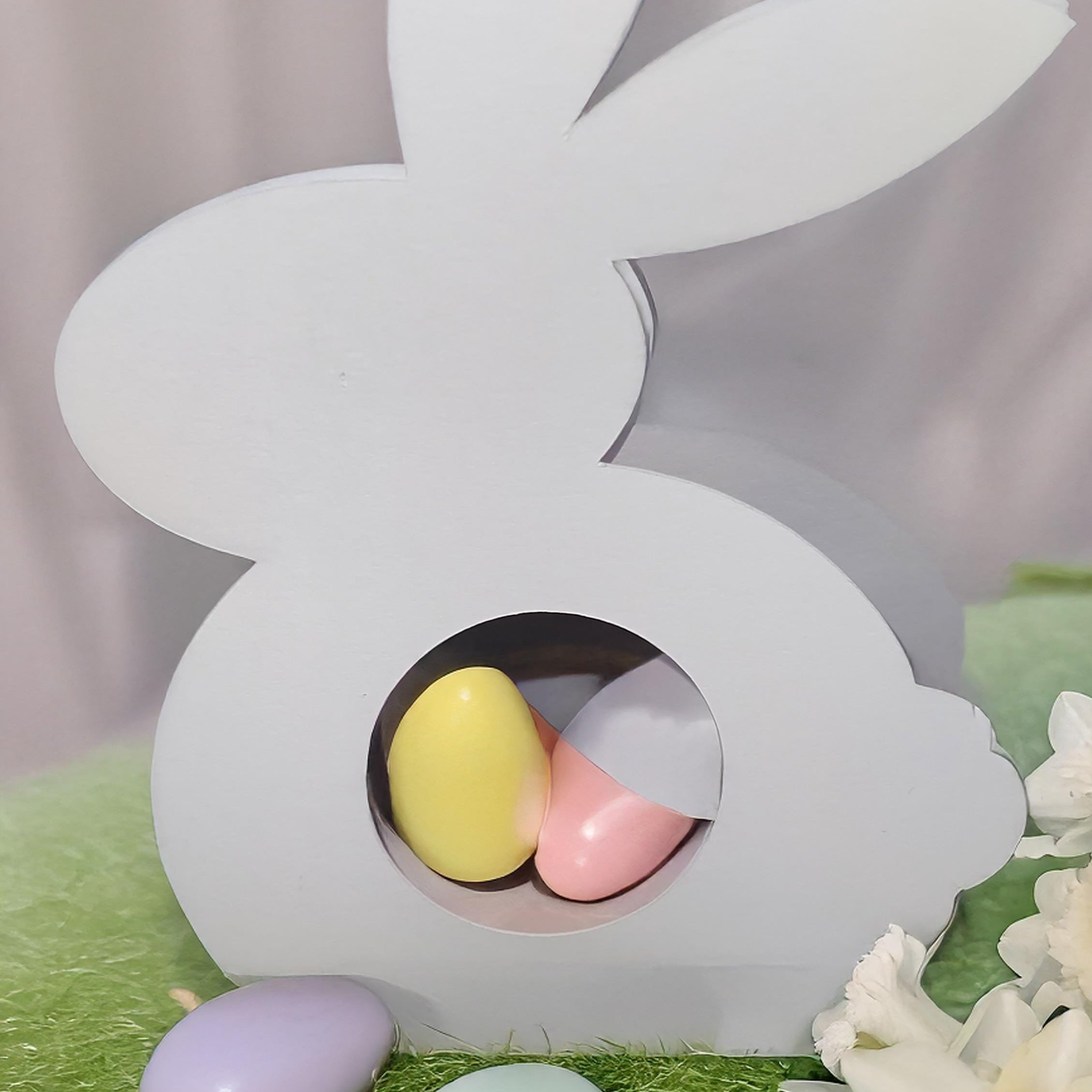 White Easter Bunny Chocolate Holder with pastel-colored mini egg treats inside on green grass background