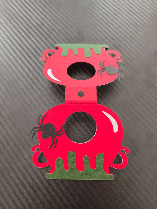 Red and green Halloween lollipop holder designed like a cauldron with spider embellishments.