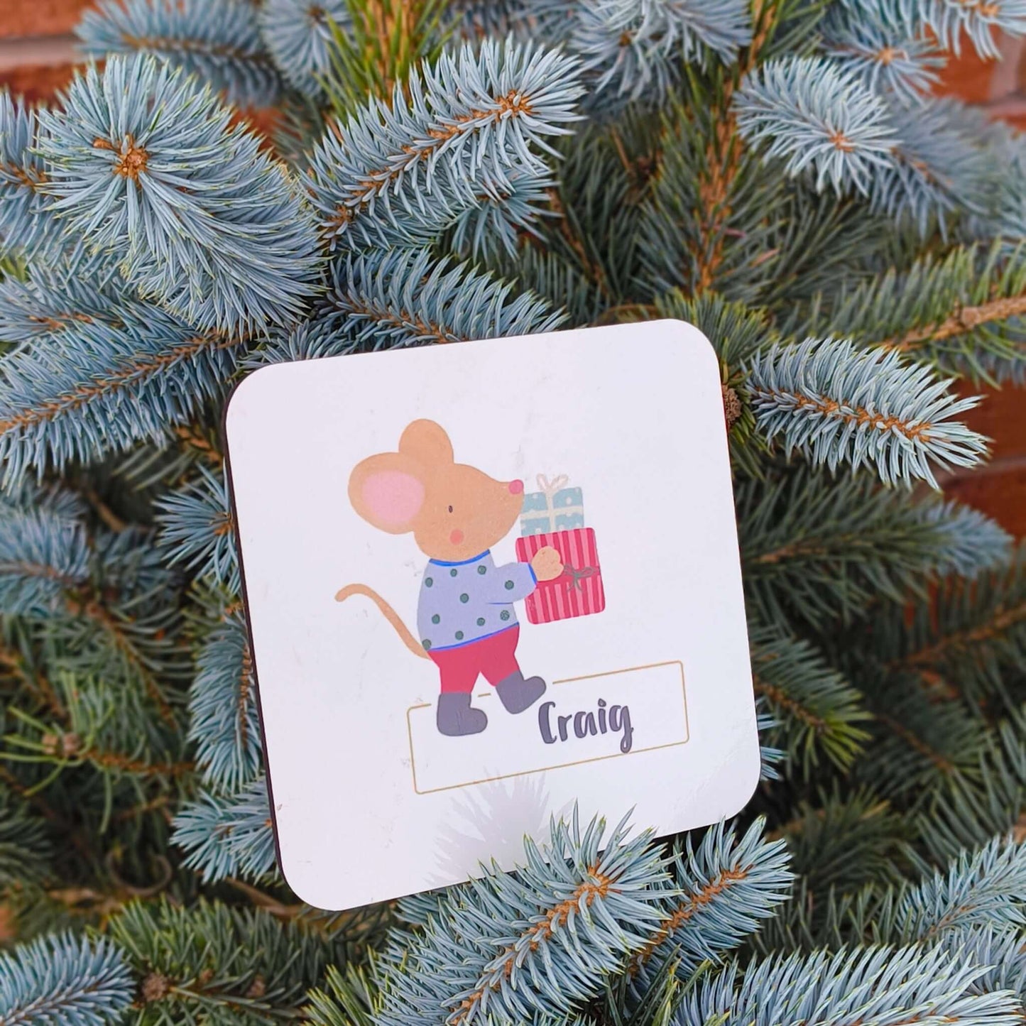 Personalised Christmas mouse coaster with a mouse holding a gift, customized with the name Craig.