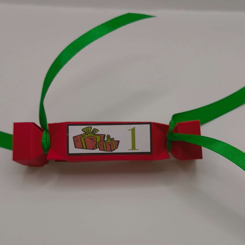 Red handmade Christmas cracker with green ribbon and number 1 gift design label