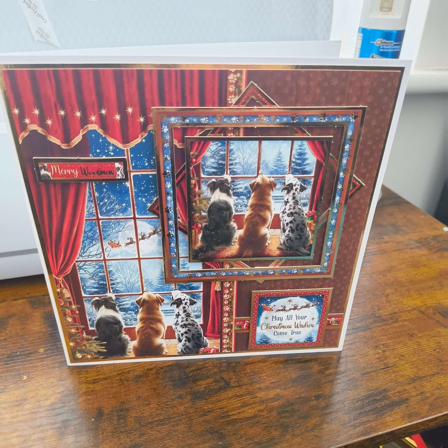 Handmade Christmas card featuring three dogs watching Santa’s sleigh through a snowy window, layered 3D design with red curtains and festive details.