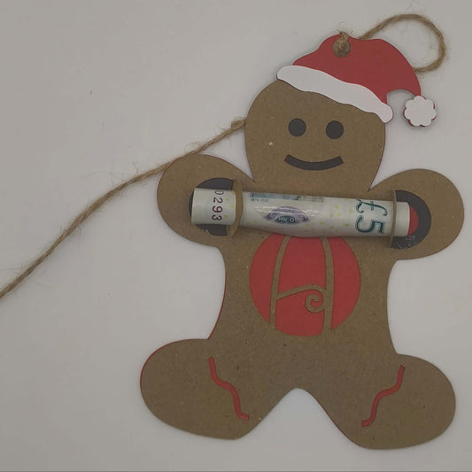 Gingerbread man ornament lying flat with rolled money gift secured in arms, showing red backing and monogram A.