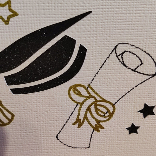 Close-up of handmade graduation card showing gold stars, diploma with ribbon, and black mortarboard on ivory textured cardstock.