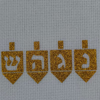Close-up view of four golden glitter dreidels with Hebrew letters (Shin, Hey, Gimel, Nun) ironed onto white textured hessian fabric. The sparkling vinyl contrasts against the crisp weave of the bag, celebrating the Hanukkah tradition with a handmade feel.