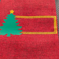 Personalised Christmas wine bottle bag in red hessian with green tree design and gold frame for a custom name.