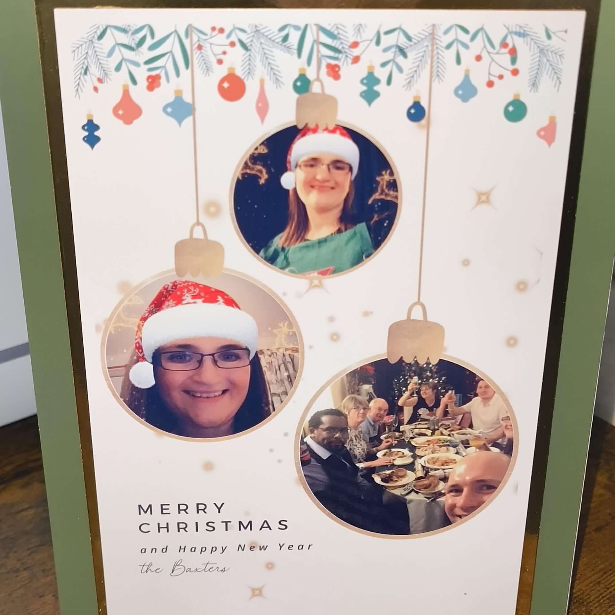 Custom family Christmas card – close-up front angle – personalised festive photo card with bauble design and green border.