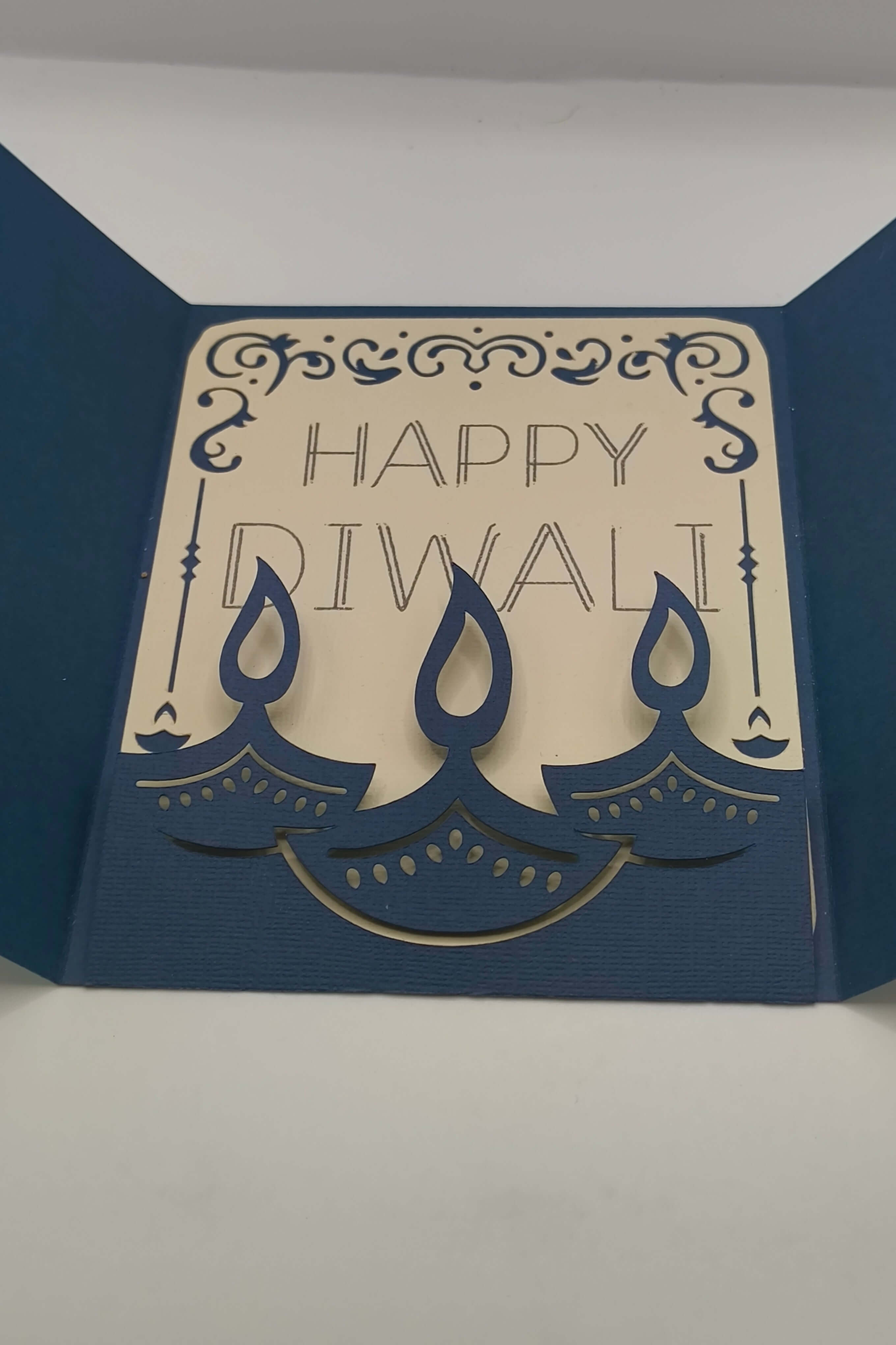 Handmade Diwali card featuring navy blue design with gold accents and layered candles, saying 'Happy Diwali' inside.