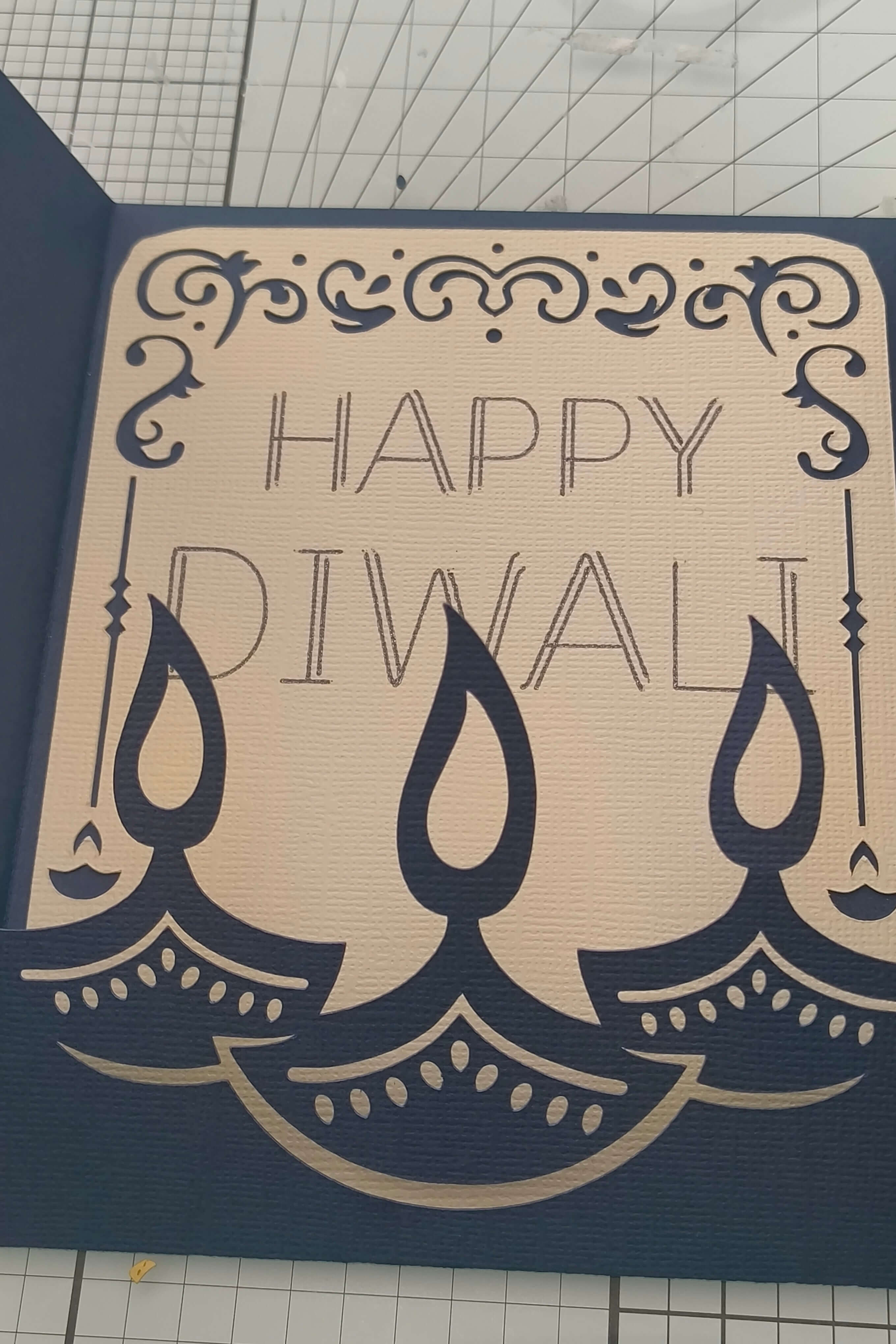 Handmade Diwali card featuring intricate design with the text 'Happy Diwali' and decorative oil lamps.