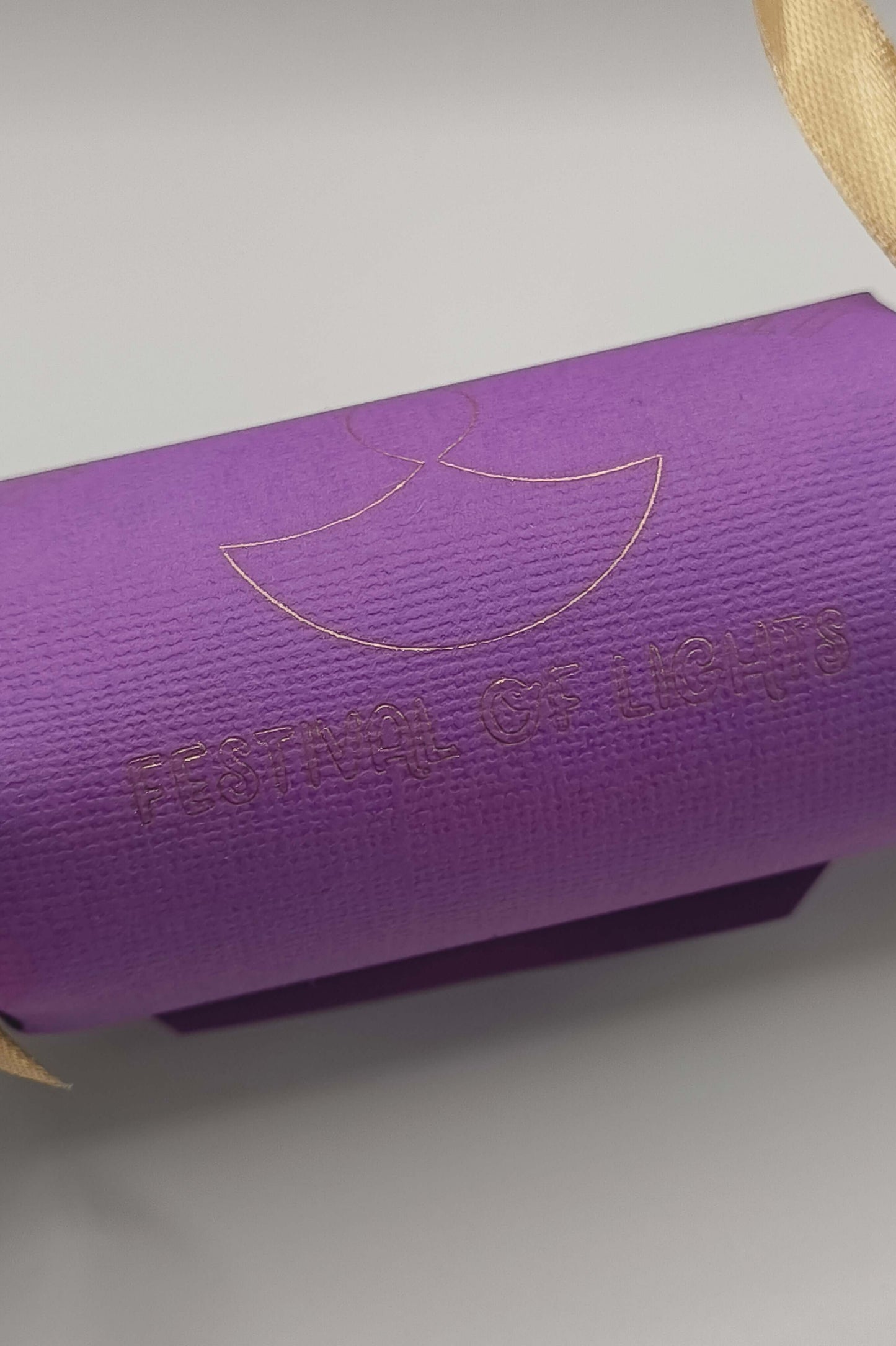 Rear view of purple Diwali cracker with gold foiled “Festival of Lights” text and diya symbol.