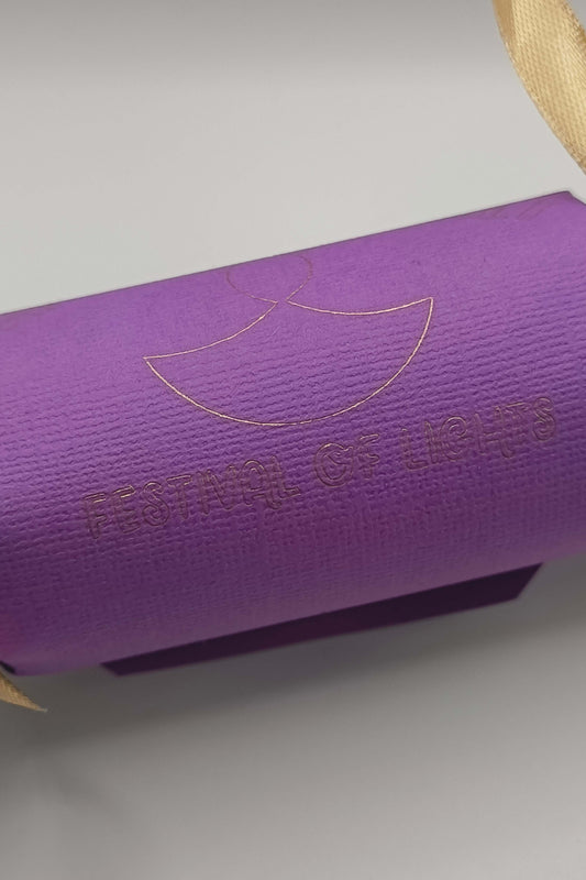 Rear view of purple Diwali cracker with gold foiled “Festival of Lights” text and diya symbol.