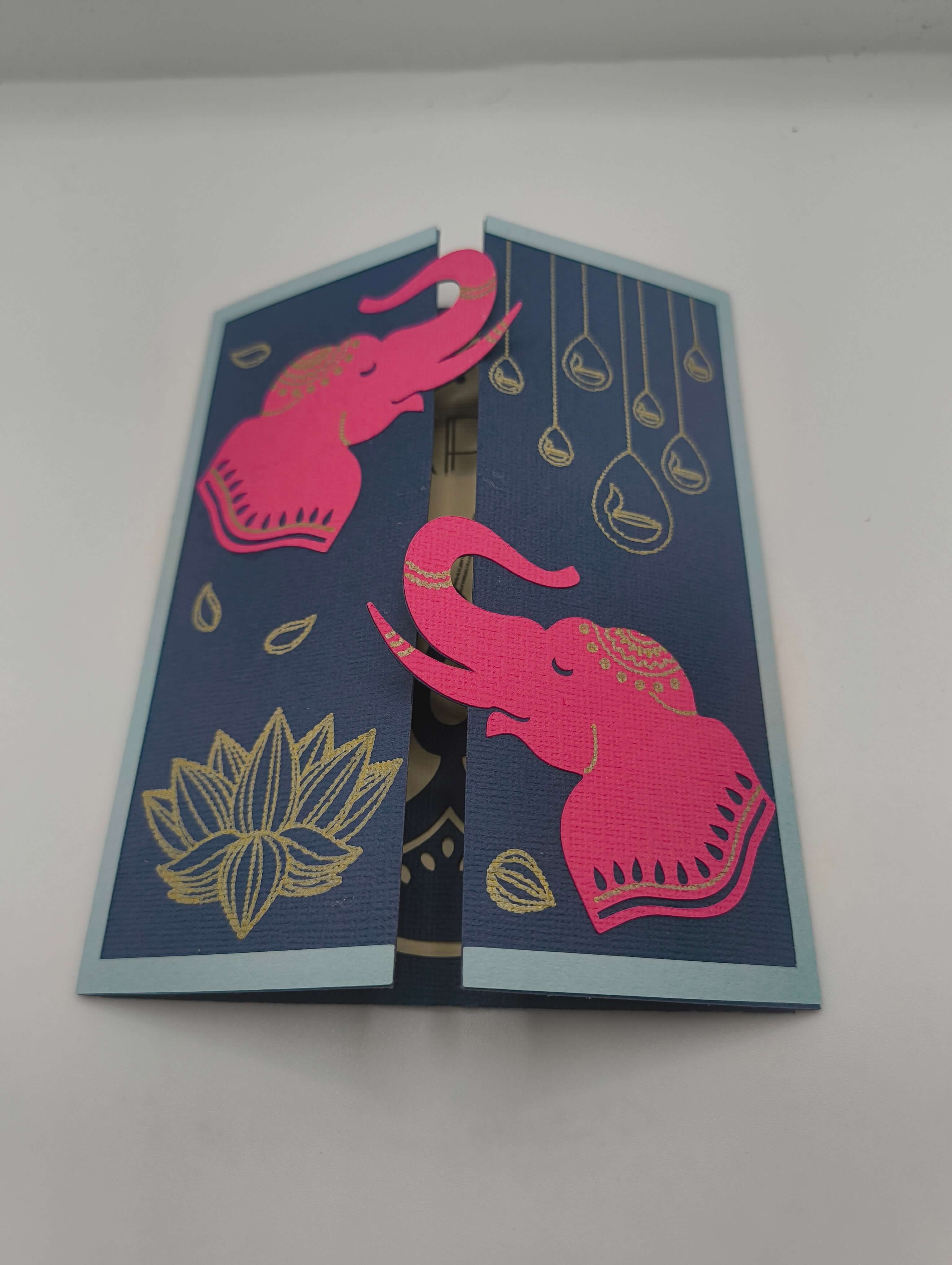 Handmade Diwali card featuring pink elephants and gold lotus on navy background for festive celebrations.