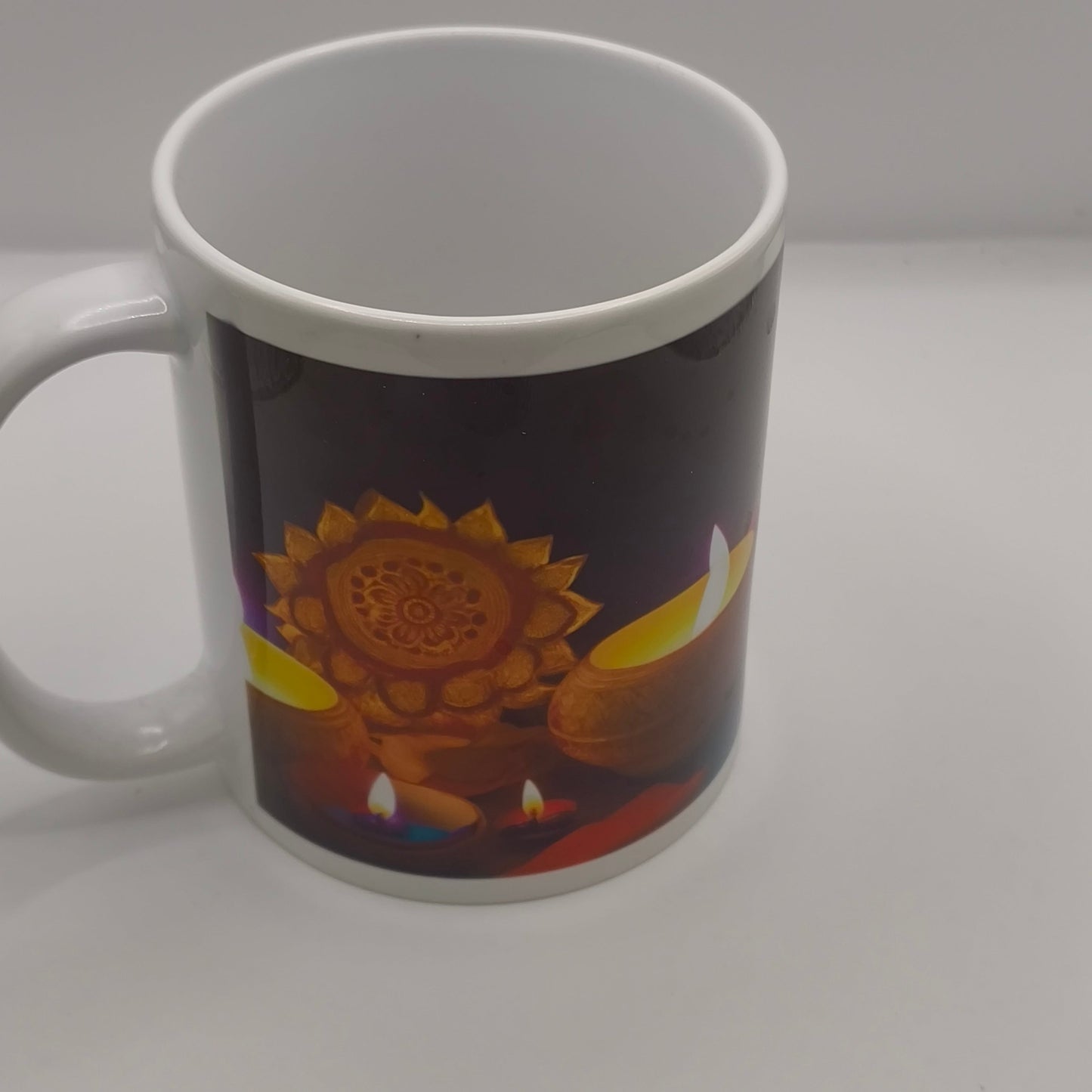 White ceramic mug featuring a Diwali design with glowing diyas and a golden mandala pattern, photographed on a clean white background to show the vibrant print detail.