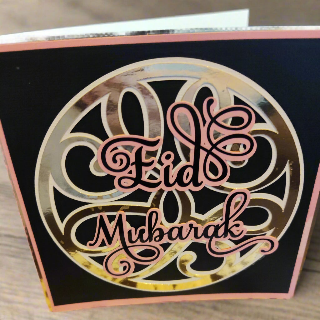 Side angle view of the Eid Mubarak card showing the shimmer of the gold foiling and layered pink detailing against the bold black base.