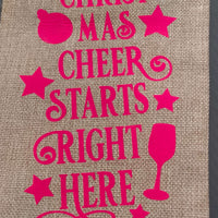 Funny Christmas wine bag with pink lettering saying 'Christmas Cheer Starts Right Here' on hessian fabric.
