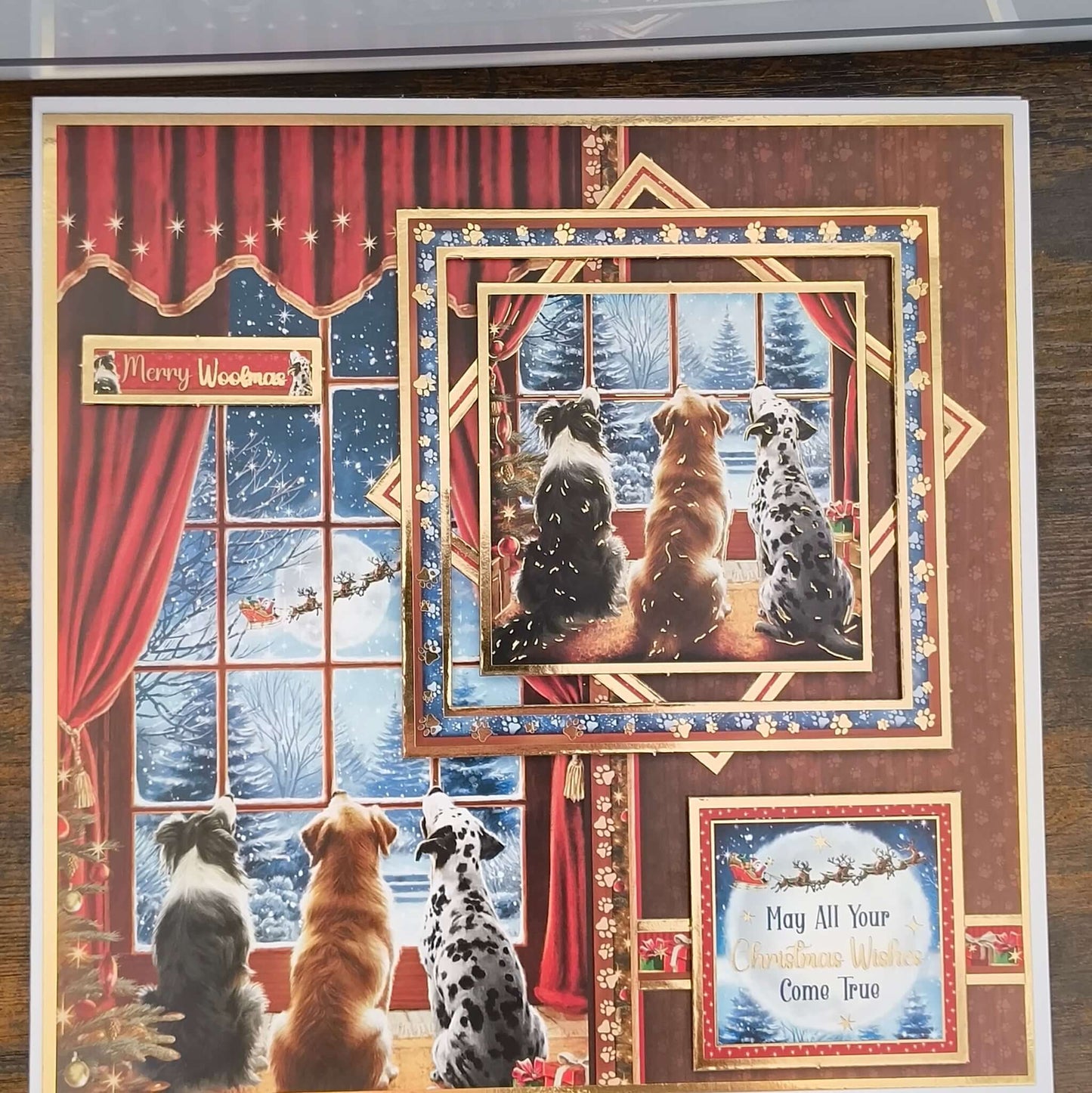 Close-up of handmade Christmas card with three dogs sitting by a snowy window, greeting reads “May All Your Christmas Wishes Come True.”