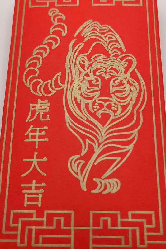 Close-up of tiger illustration in gold pen on red Chinese New Year envelope.
