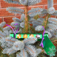 Personalised chocolate cracker gift decorated with colourful treats hanging from a Christmas tree.
