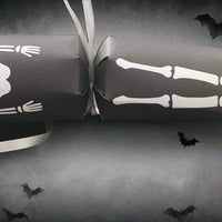Halloween skeleton cracker with bones and ribcage design on black card, decorated with flying bat background.