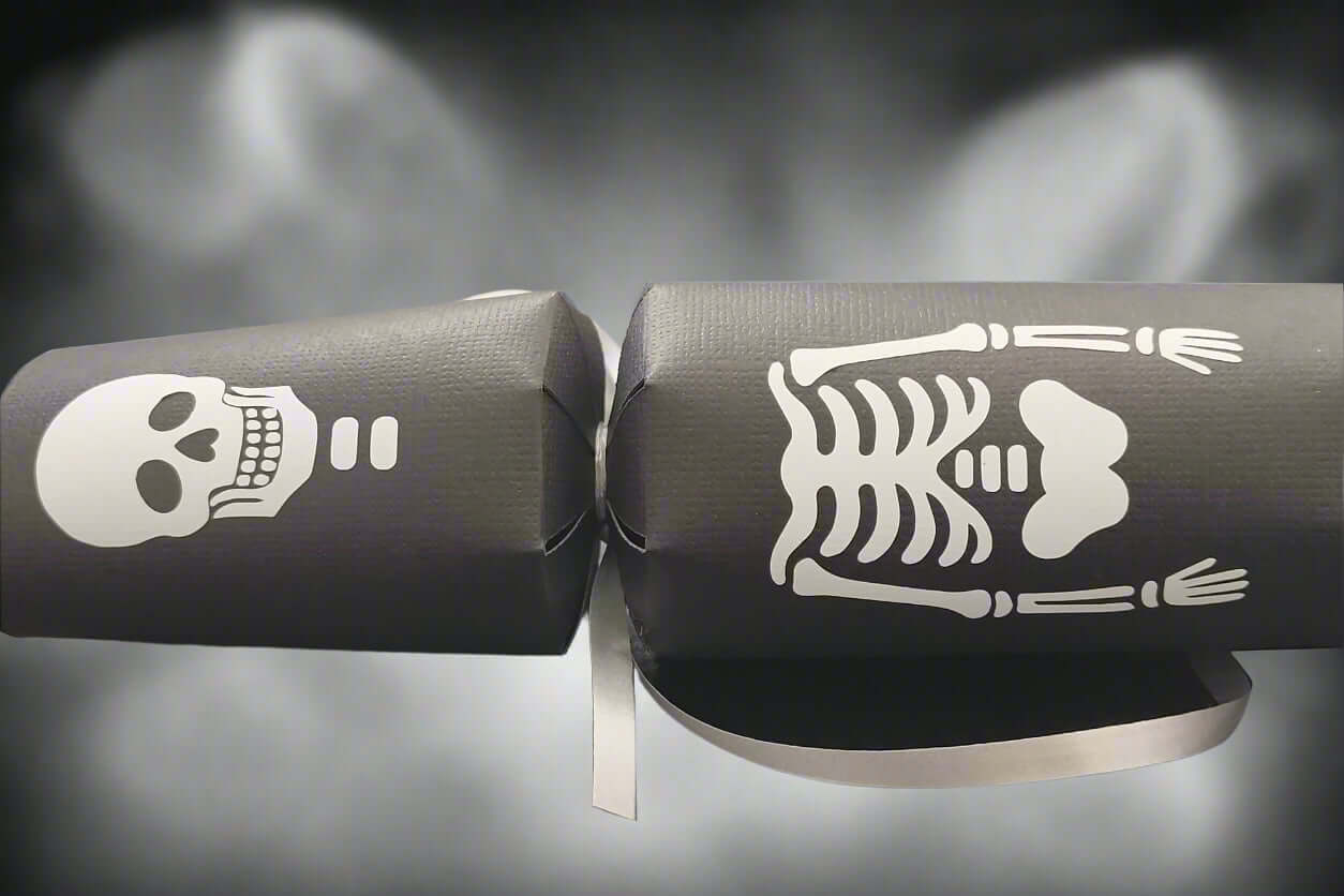 Close-up of black Halloween cracker featuring skull and ribcage skeleton design with silver ribbon.