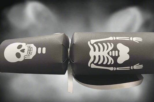 Close-up of black Halloween cracker featuring skull and ribcage skeleton design with silver ribbon.