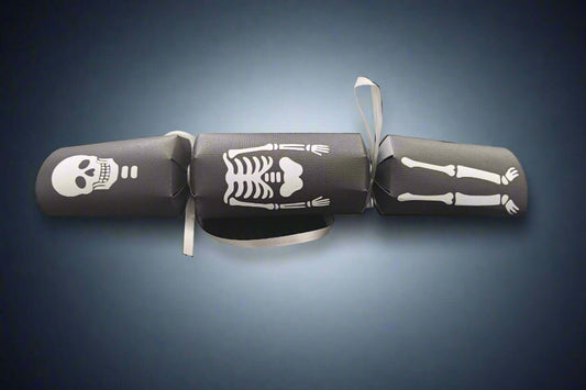Black Halloween cracker with white skeleton design showing skull, ribcage, and legs tied with silver ribbon.