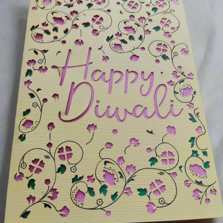 Detailed view of Happy Diwali handmade greeting card with pink cut-out lettering and floral designs, layered with green accents.
