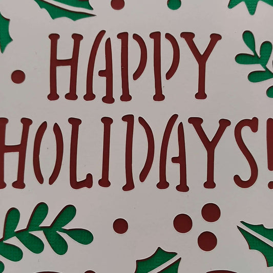 Close-up of handmade festive Happy Holidays card with red lettering and green backing.