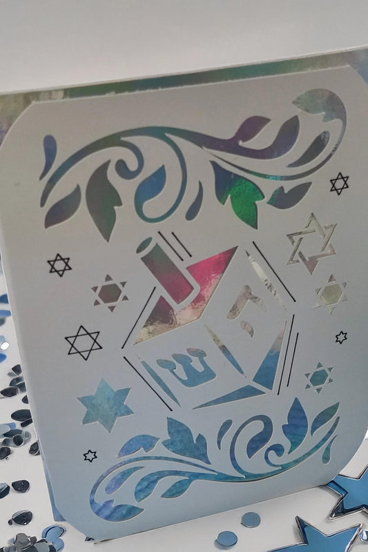 Handmade Hanukkah card with dreidel and Star of David cut-out design, holographic background